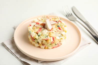 Delicious salad with fresh crab sticks on white table