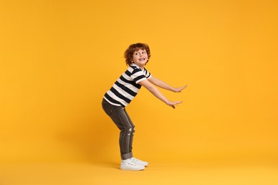 Happy little boy dancing on yellow background