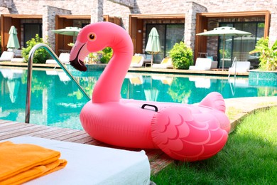 Float in shape of flamingo on wooden deck near swimming pool and sunbeds at luxury resort