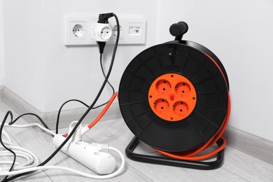 Extension cord reel plugged into socket indoors. Electrician's equipment