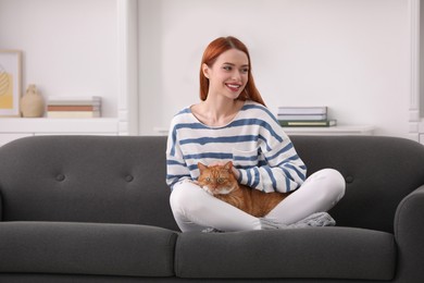 Happy woman with her cute cat on sofa at home