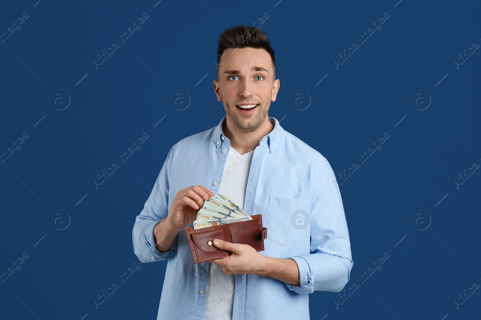Photo of Happy man with cash money and wallet on blue background