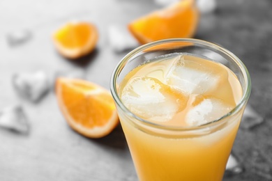 Glass of orange juice with ice cubes on table, closeup. Space for text