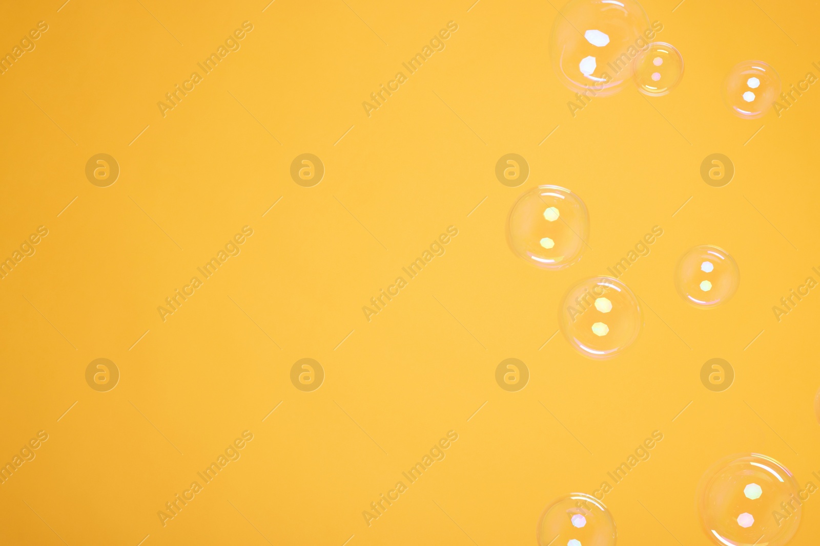 Photo of Many beautiful soap bubbles on orange background. Space for text