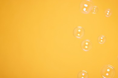 Photo of Many beautiful soap bubbles on orange background. Space for text