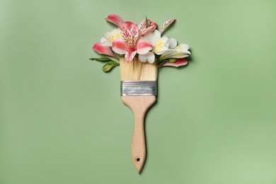 Photo of Composition with painting brush and beautiful alstroemerias on green background, top view. Creative concept