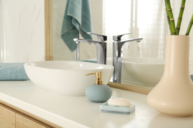 Photo of Vessel sink and toiletries near mirror in bathroom