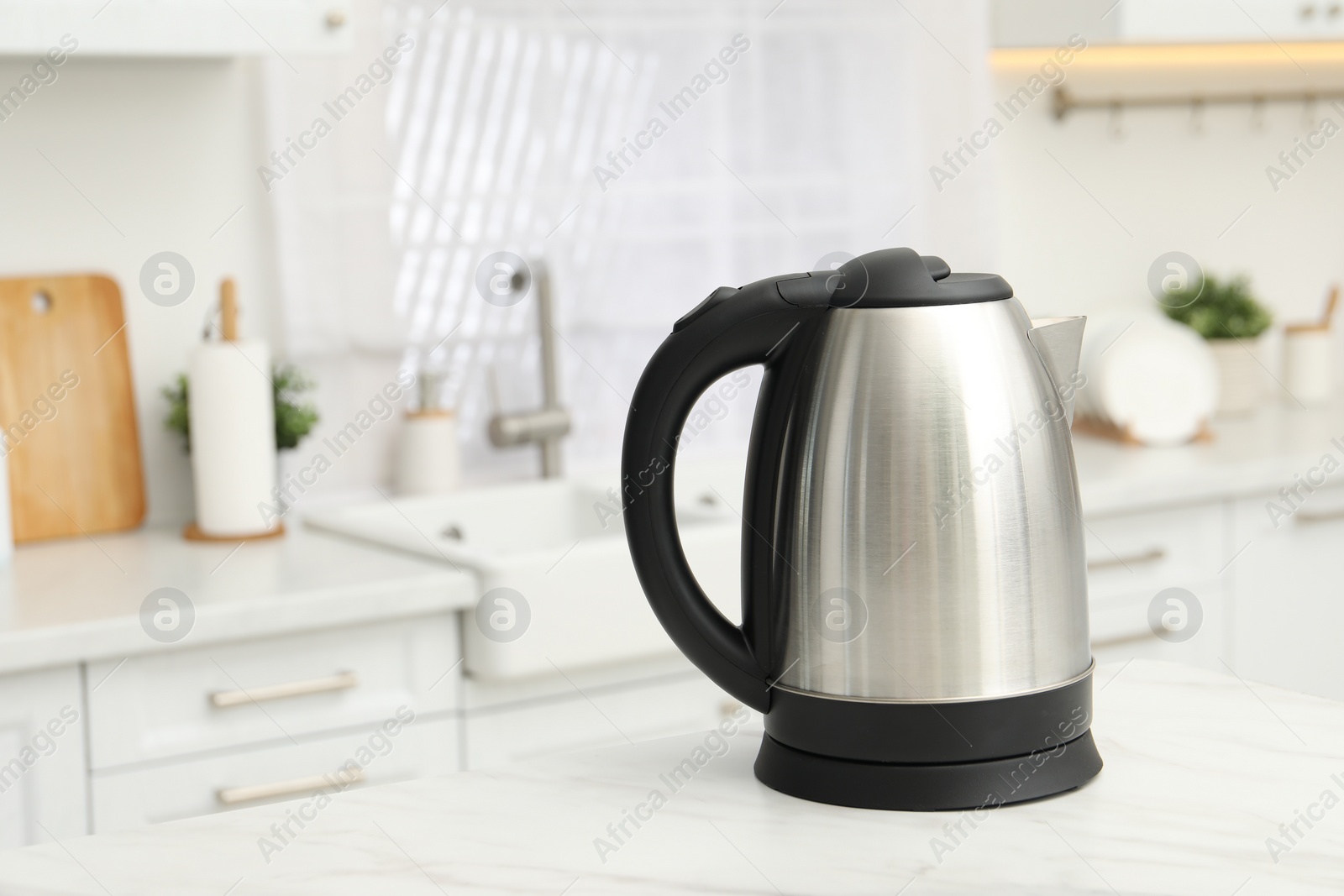 Photo of Modern electric kettle on table in kitchen. Space for text