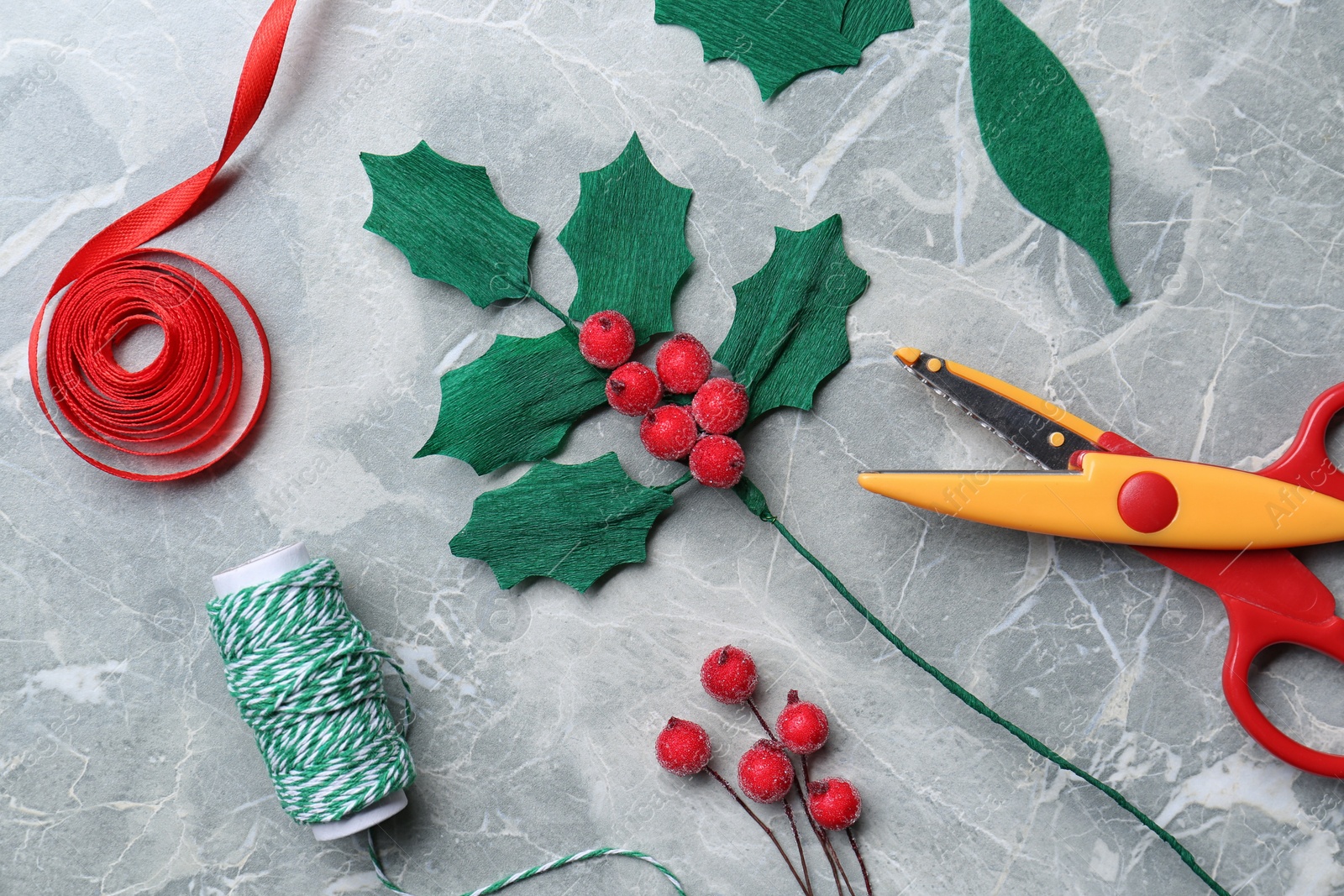 Photo of Set of instruments and materials for making mistletoe branch on grey table, flat lay