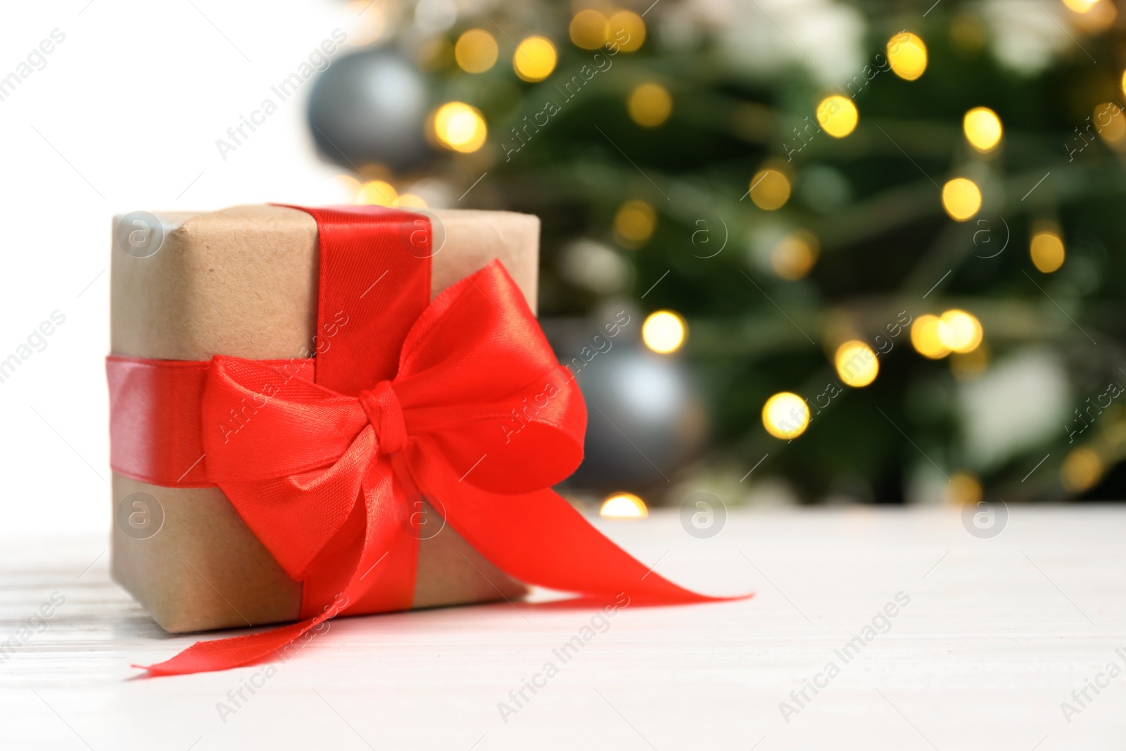 Photo of Beautiful gift box and blurred Christmas tree on background