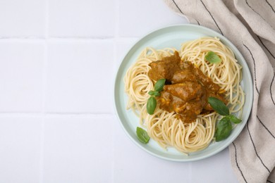 Delicious pasta and chicken with curry sauce on white tiled table, top view. Space for text