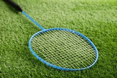 Photo of Badminton racket on green grass outdoors, closeup