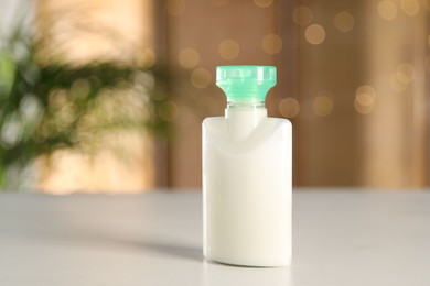 Photo of Mini bottle of cosmetic product on white table against blurred background. Space for text