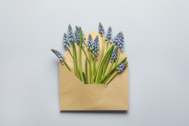 Photo of Envelope with beautiful spring muscari flowers on grey background, top view