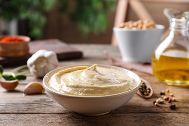 Photo of Delicious creamy hummus in dish on wooden table