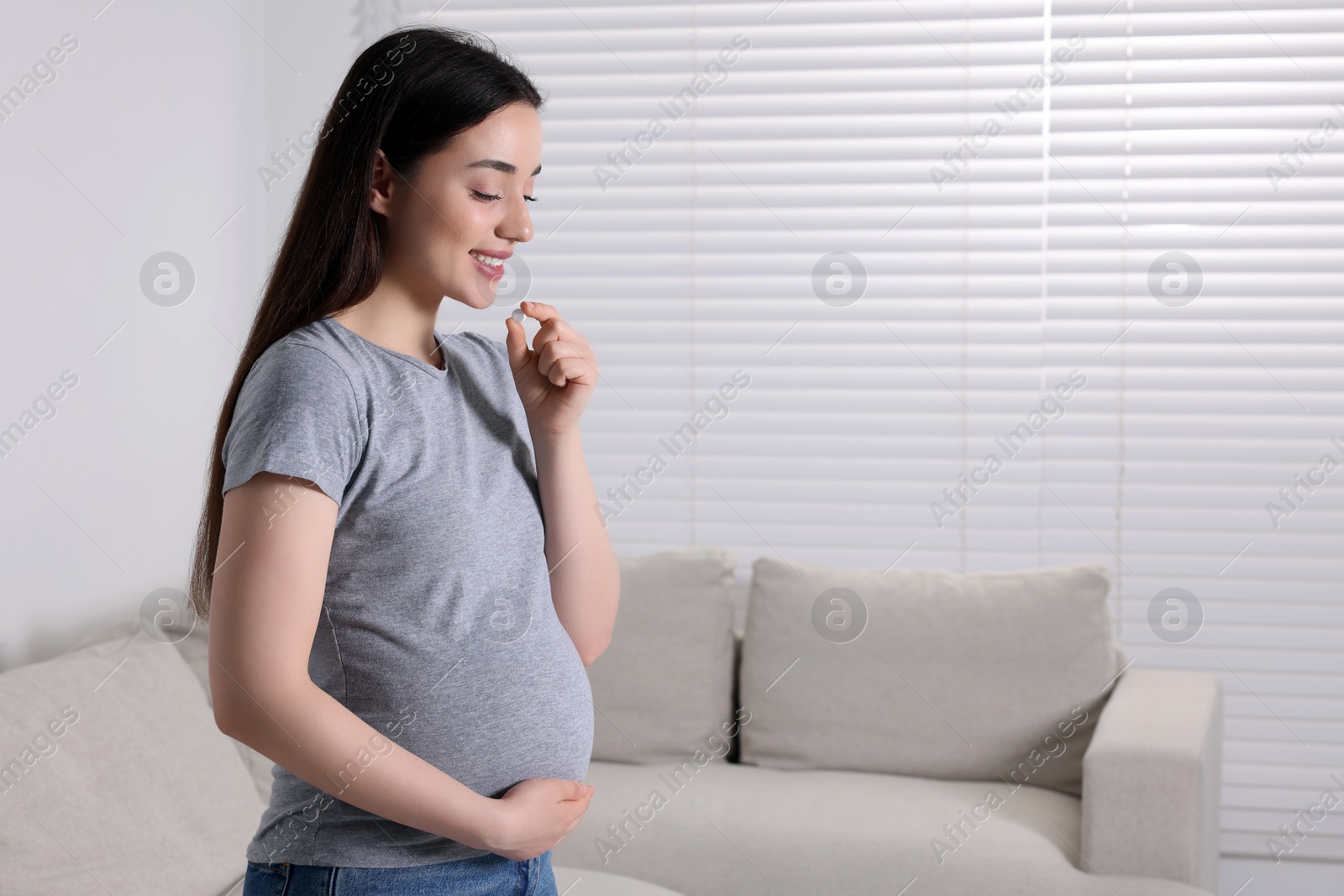 Photo of Pregnant woman taking pill at home, space for text