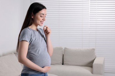 Photo of Pregnant woman taking pill at home, space for text