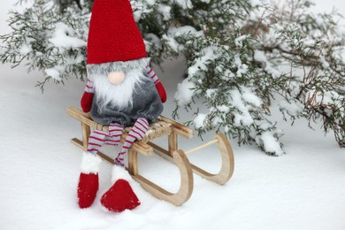 Photo of Wooden sleigh with Christmas gnome on snow outdoors