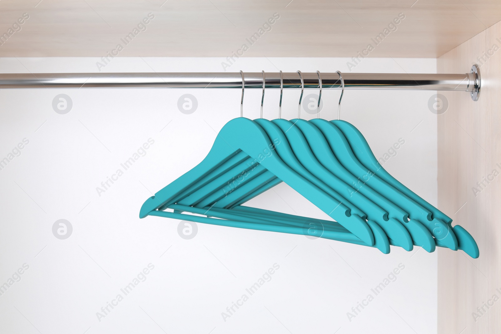 Photo of Clothes hangers on metal rail in wardrobe