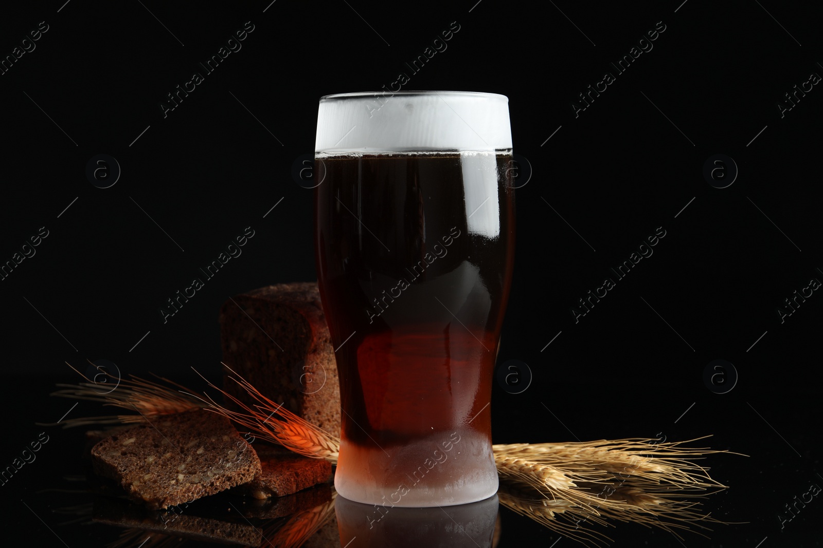 Photo of Delicious cold kvass, bread and spikes on black background