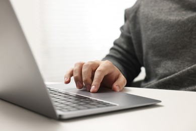 E-learning. Young man using laptop at white table, closeup