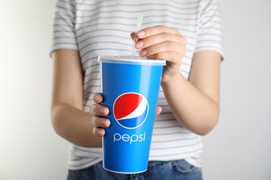 Photo of MYKOLAIV, UKRAINE - JUNE 9, 2021: Woman holding paper Pepsi cup on light background, closeup