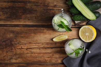Tasty fresh cucumber water and ingredients on wooden table, flat lay. Space for text