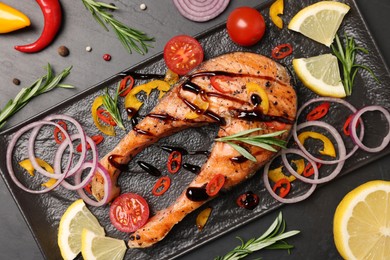 Photo of Tasty salmon steak served on black table, flat lay