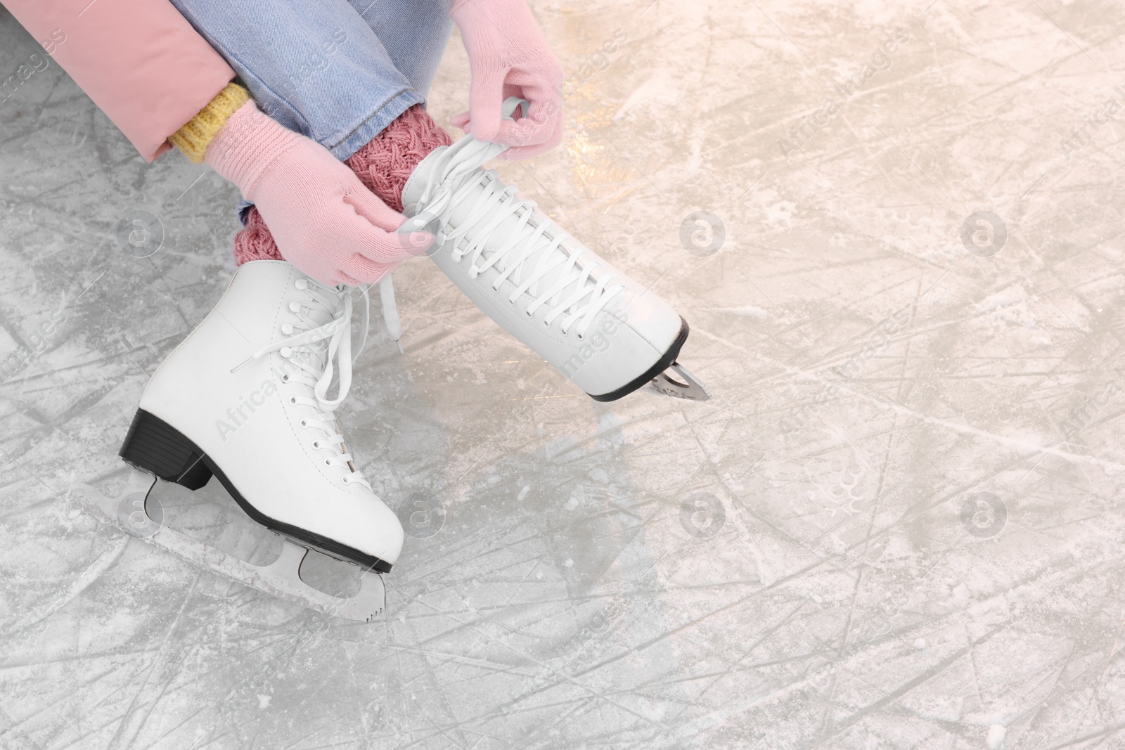 Photo of Woman lacing figure skates on ice, above view