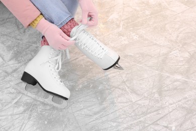 Woman lacing figure skates on ice, above view