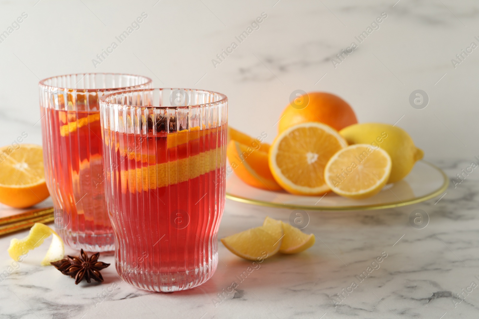 Photo of Aromatic punch drink and ingredients on white marble table. Space for text