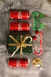 Photo of MYKOLAIV, UKRAINE - January 01, 2021: Flat lay composition with Coca-Cola cans and Christmas decorations on fur background