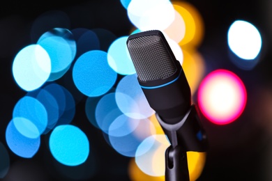 Microphone against festive lights, space for text. Musical equipment