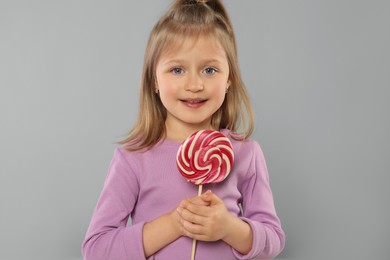 Portrait of happy girl with lollipop on light grey background