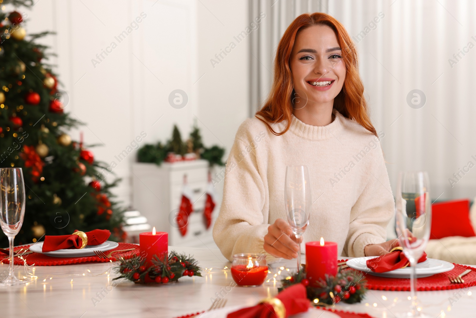 Photo of Beautiful young woman setting table in room decorated for Christmas