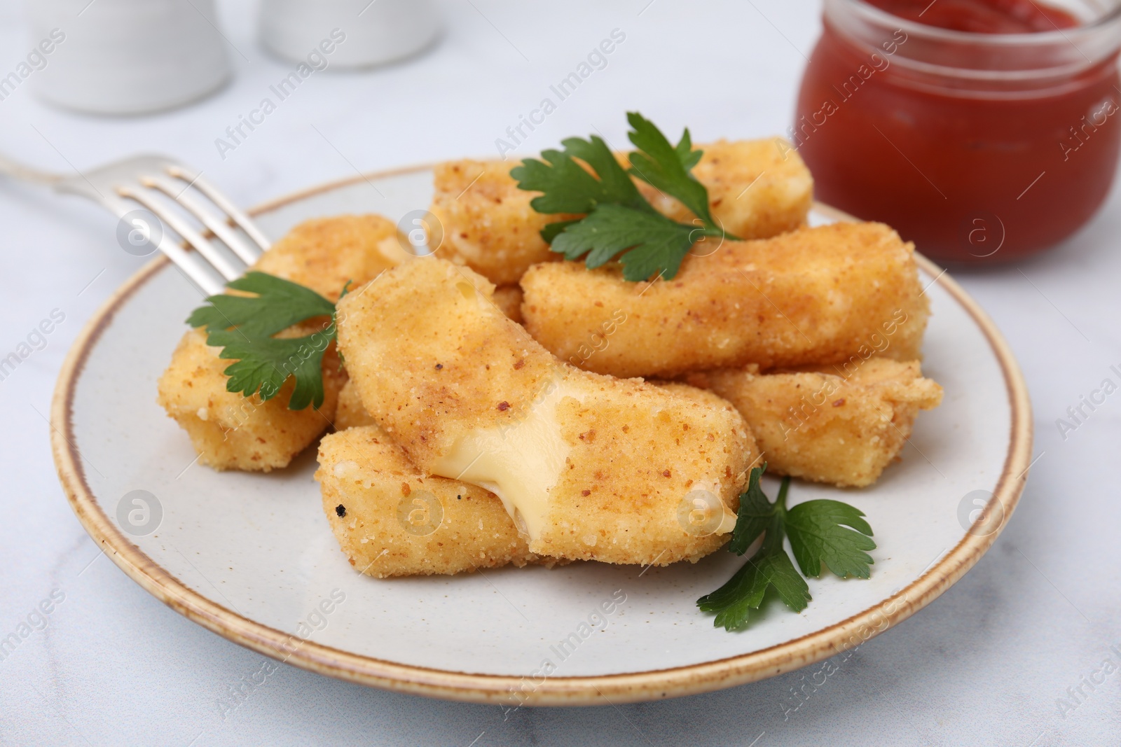 Photo of Plate with tasty fried mozzarella sticks and parsley on light table, closeup