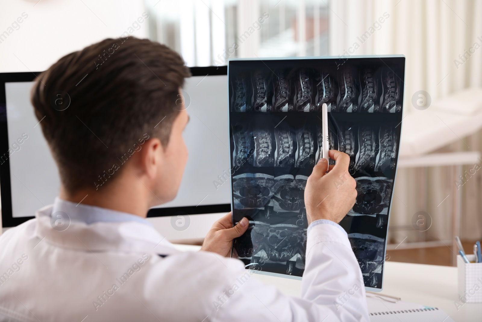 Photo of Orthopedist examining X-ray picture at desk in clinic