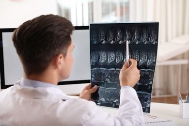 Orthopedist examining X-ray picture at desk in clinic