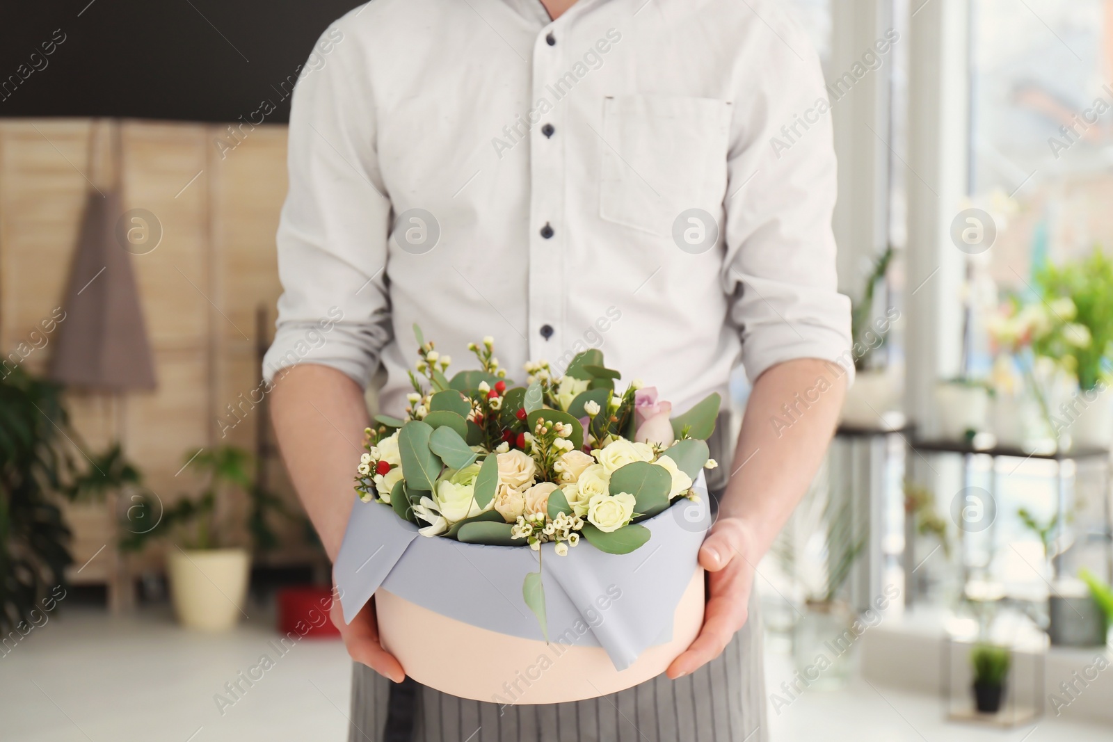 Photo of Male florist holding box with flowers at workplace