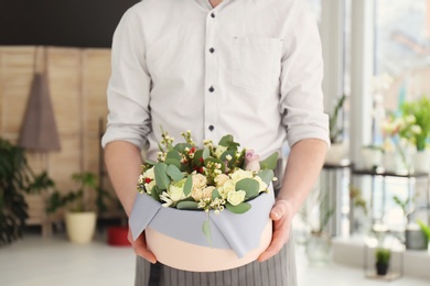 Male florist holding box with flowers at workplace