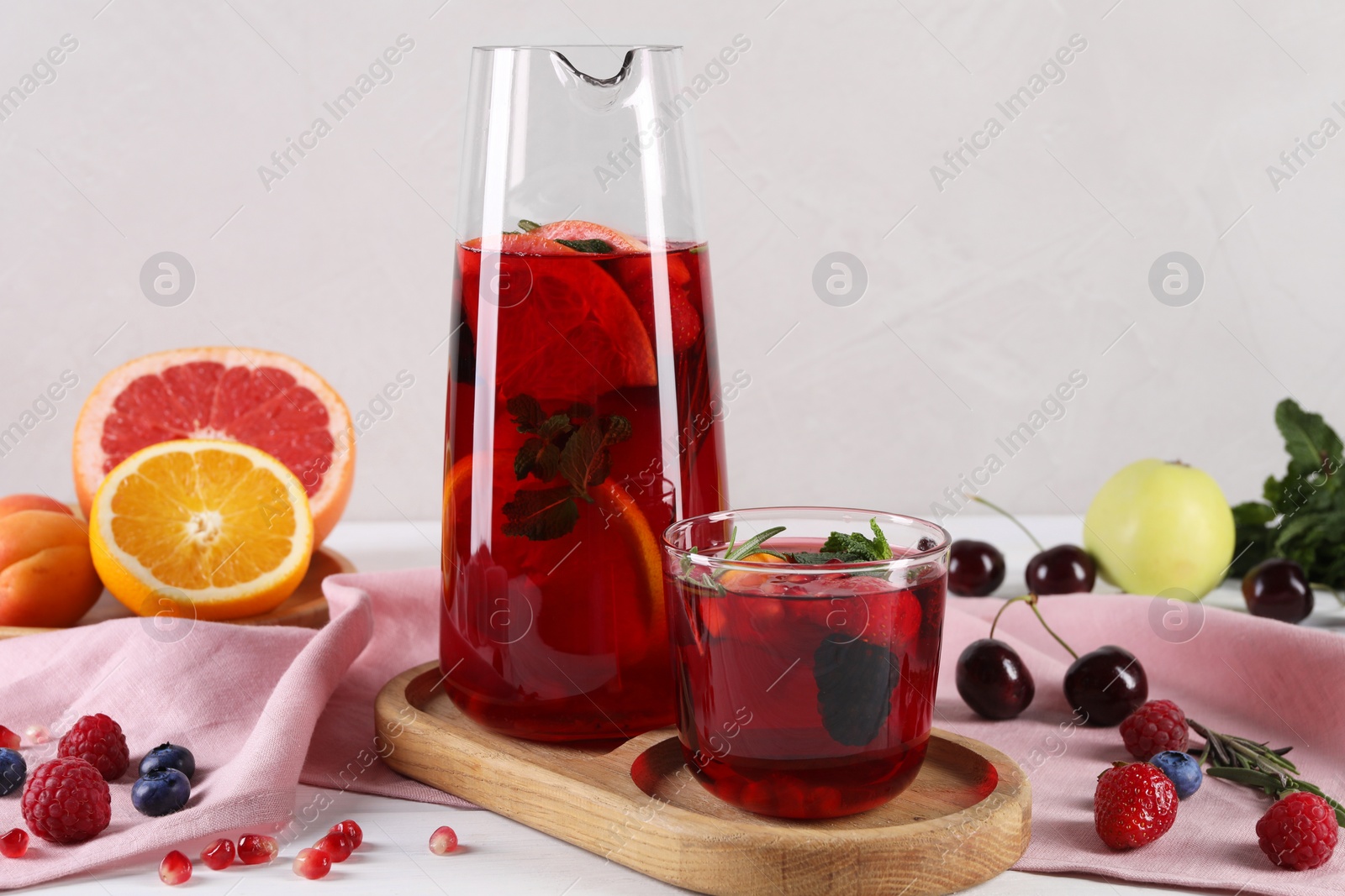 Photo of Glass of delicious sangria, fruits and berries on table