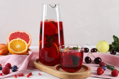 Photo of Glass of delicious sangria, fruits and berries on table