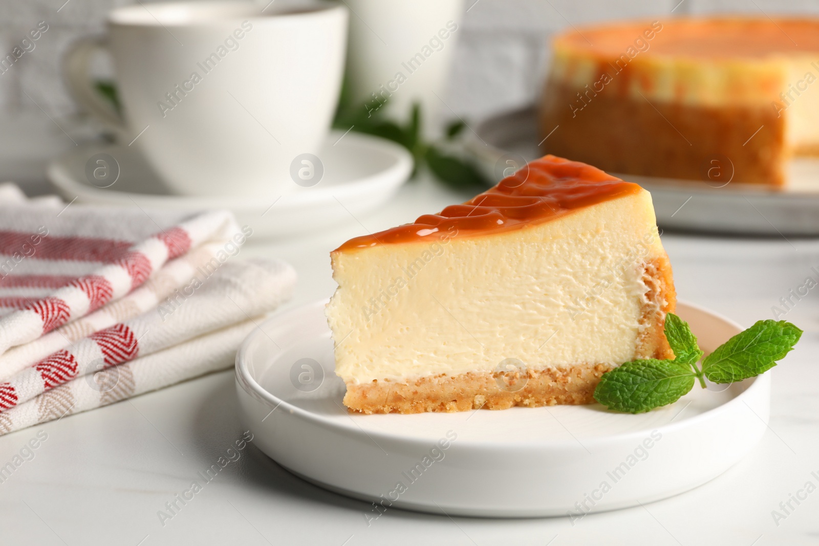 Photo of Piece of delicious caramel cheesecake served on white marble table, closeup