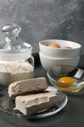 Photo of Compressed yeast, eggs and flour on grey wooden table