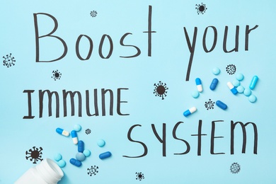 Photo of Pills on light blue sheet of paper with words Boost Your Immune System, flat lay