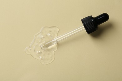 Photo of Pipette with cosmetic serum on beige background, top view