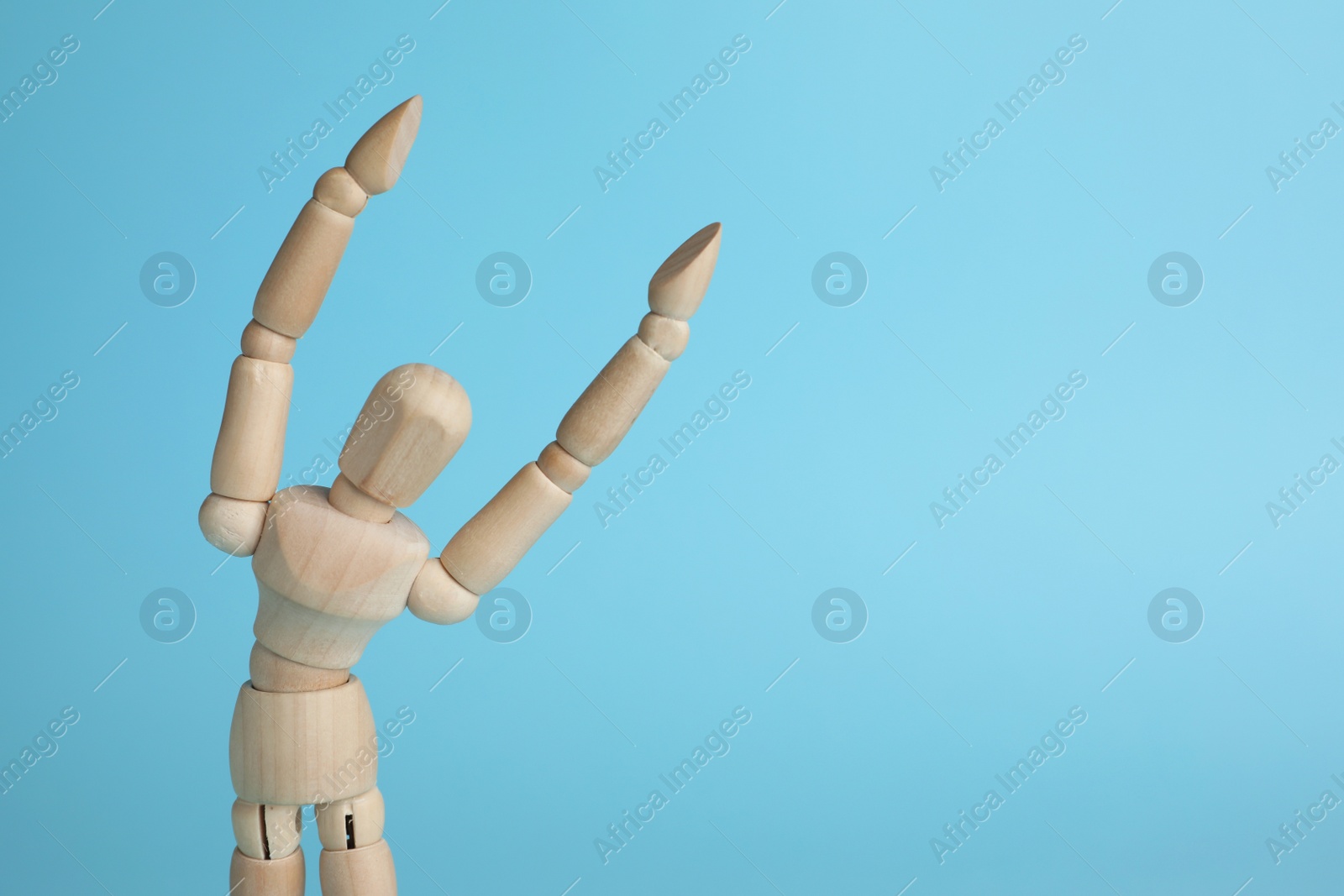 Photo of Wooden human model on light blue background, space for text. Mini mannequin