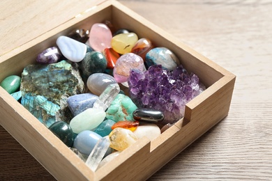 Box with different beautiful gemstones on wooden table