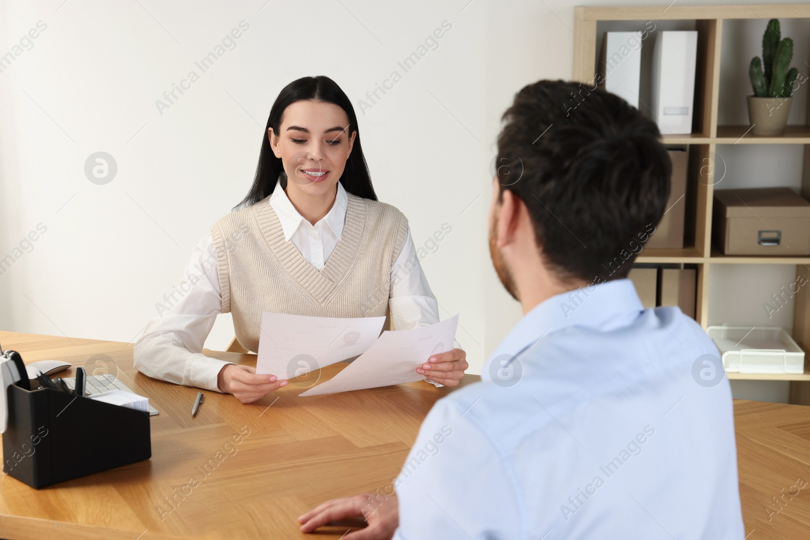 Photo of Human resources manager reading applicant's resume during job interview in office