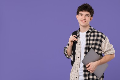 Photo of Portrait of student with backpack and laptop on purple background. Space for text